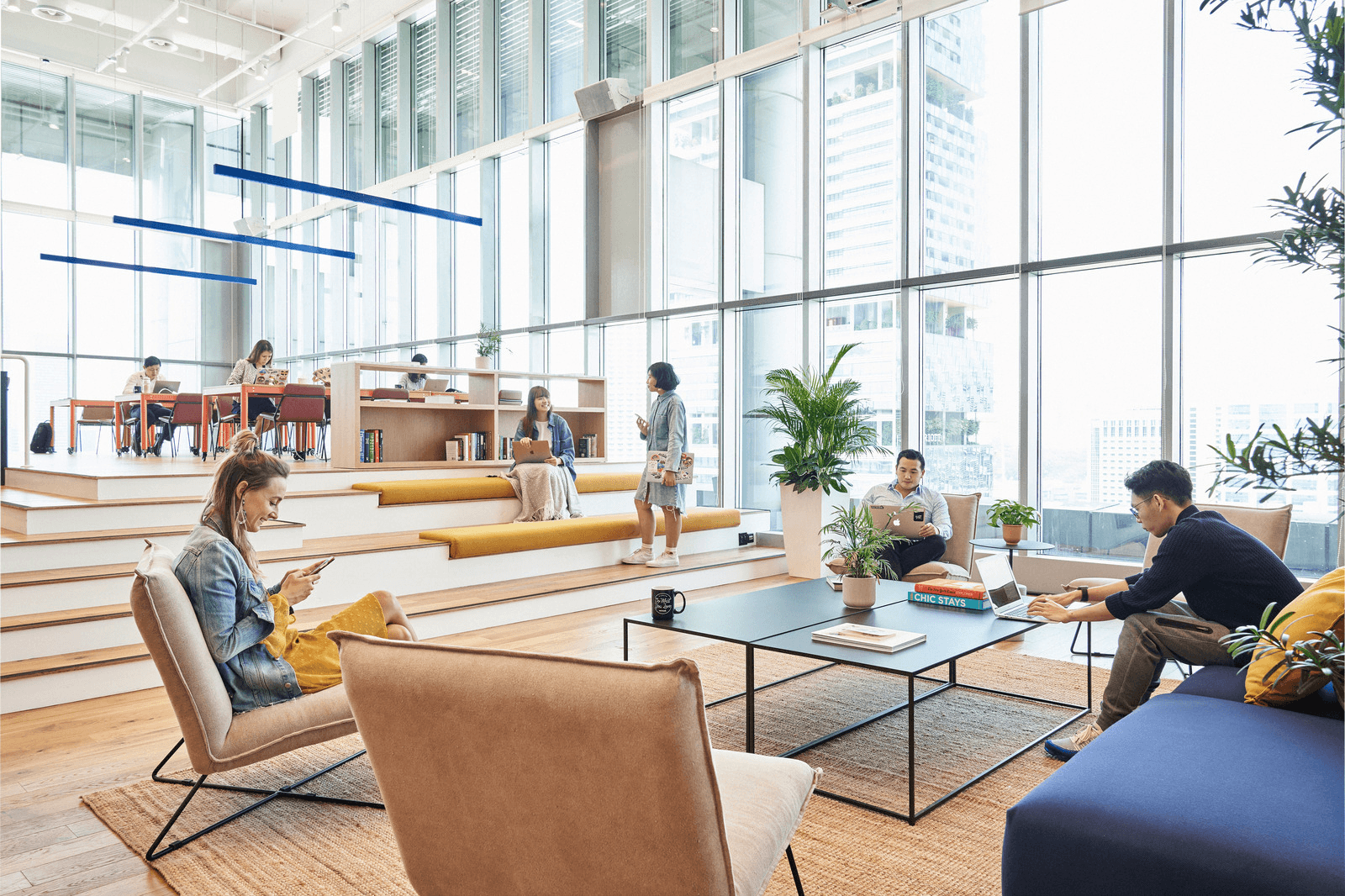 Modern co-working space with floor-to-ceiling windows, comfortable seating areas, and collaborative workspaces